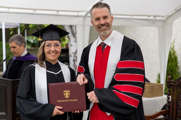 Student and Neil Fassina,  President, both holding a parchment folder at a convocation ceremony